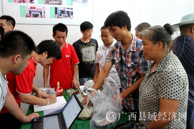 圖為貧困群眾拿農(nóng)產(chǎn)品和空店員工交易。陸榮斌 攝1_副本